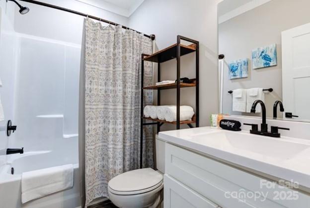 bathroom with toilet, shower / bathtub combination with curtain, and vanity