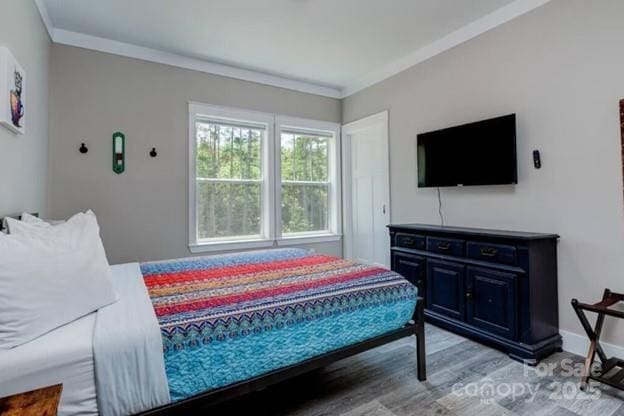 bedroom featuring ornamental molding, baseboards, and light wood finished floors