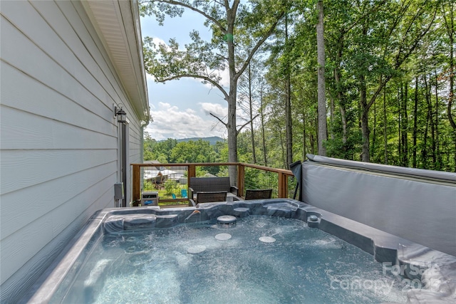 wooden deck featuring a forest view and a hot tub