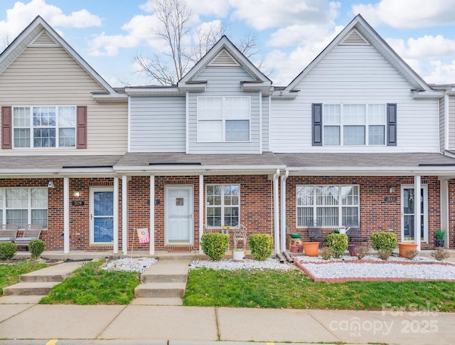 multi unit property featuring a shingled roof and brick siding