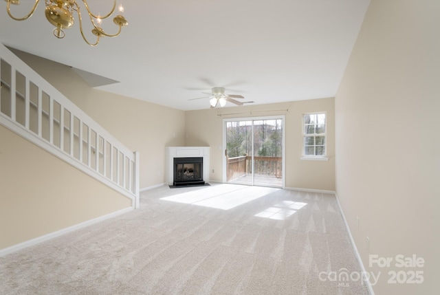 unfurnished living room with a fireplace with flush hearth, carpet, baseboards, and stairs