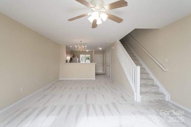 unfurnished living room featuring ceiling fan with notable chandelier, stairway, light colored carpet, and baseboards