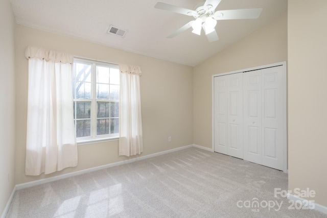 unfurnished bedroom featuring a closet, visible vents, carpet flooring, vaulted ceiling, and baseboards