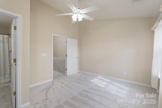 unfurnished bedroom with carpet, vaulted ceiling, baseboards, and ceiling fan