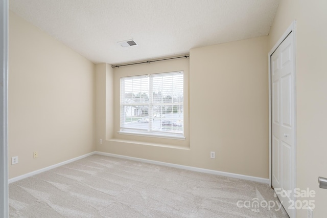 spare room with baseboards, a textured ceiling, visible vents, and light colored carpet