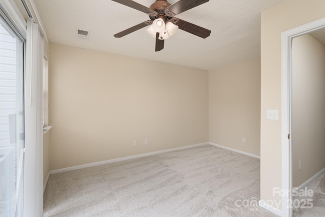 unfurnished bedroom with a textured ceiling, carpet floors, a ceiling fan, visible vents, and baseboards