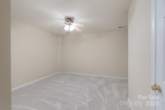 unfurnished room featuring light colored carpet, visible vents, a ceiling fan, a textured ceiling, and baseboards