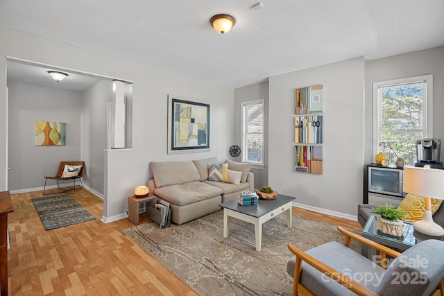 sitting room with baseboards, light wood-type flooring, and a healthy amount of sunlight