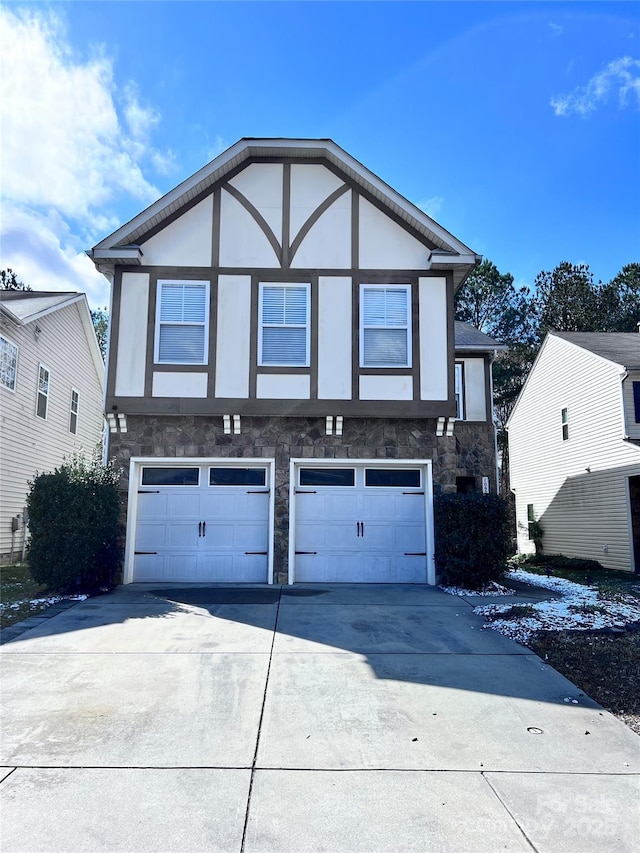 tudor house with stone siding, concrete driveway, a garage, and stucco siding