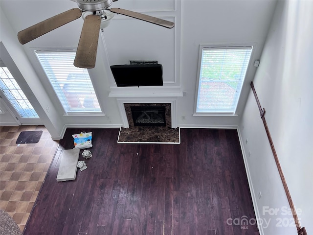 living room featuring a ceiling fan, a fireplace, baseboards, and wood finished floors