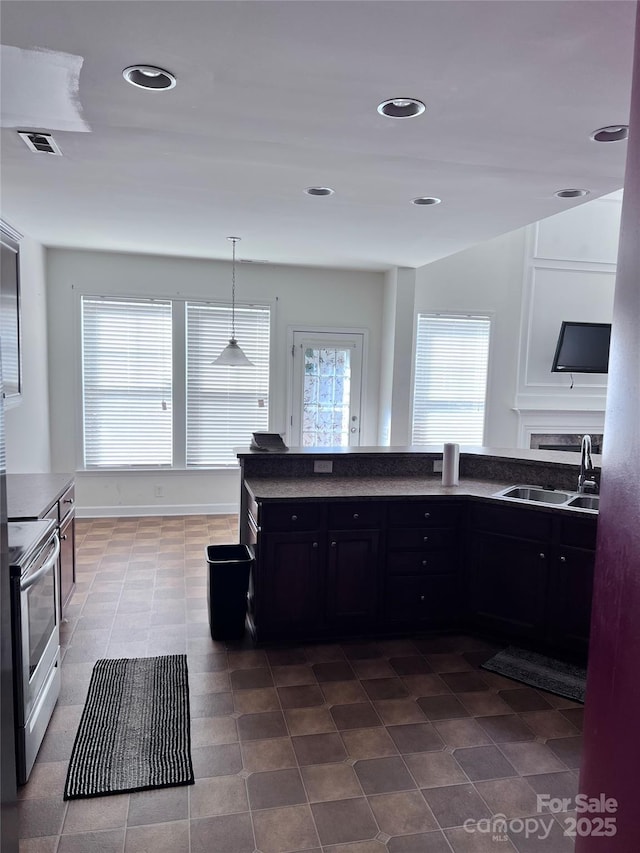 kitchen with visible vents, electric stove, dark countertops, dark cabinets, and a sink