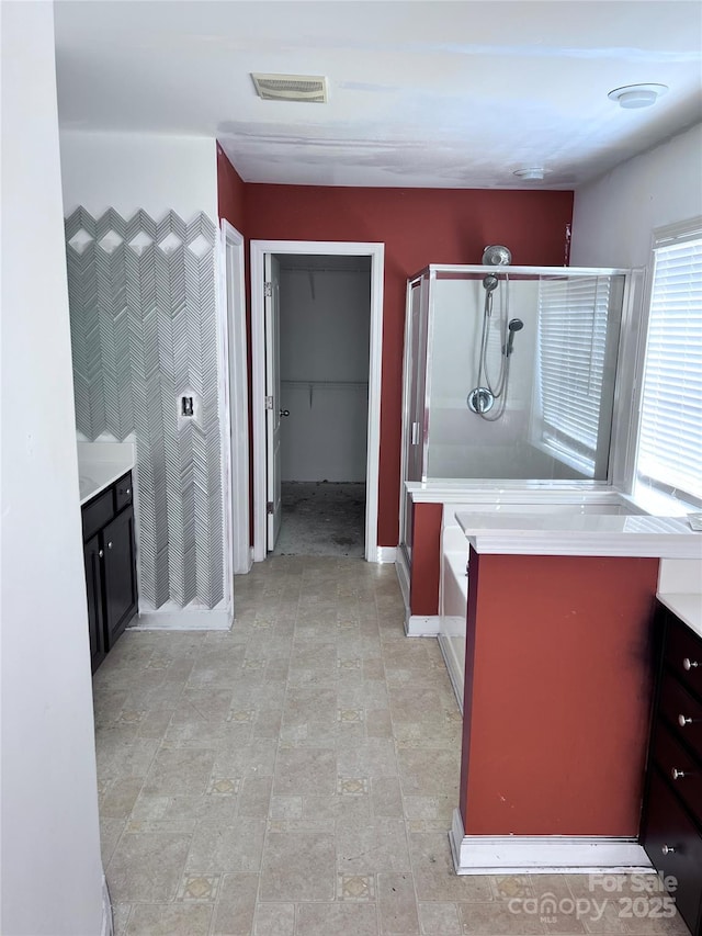 bathroom featuring vanity, a shower stall, visible vents, and a walk in closet