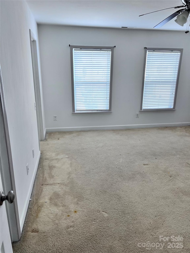 carpeted spare room with ceiling fan and baseboards