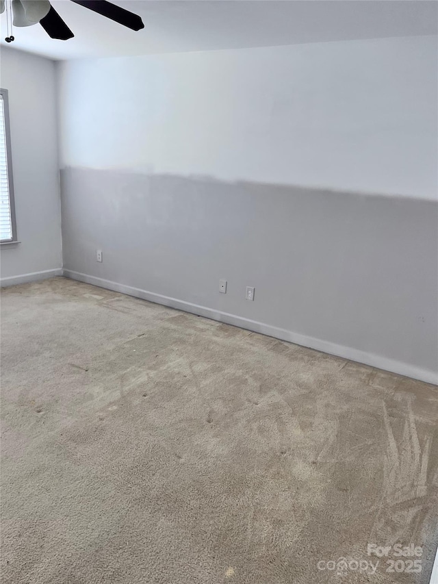 unfurnished room with carpet floors, baseboards, and a ceiling fan