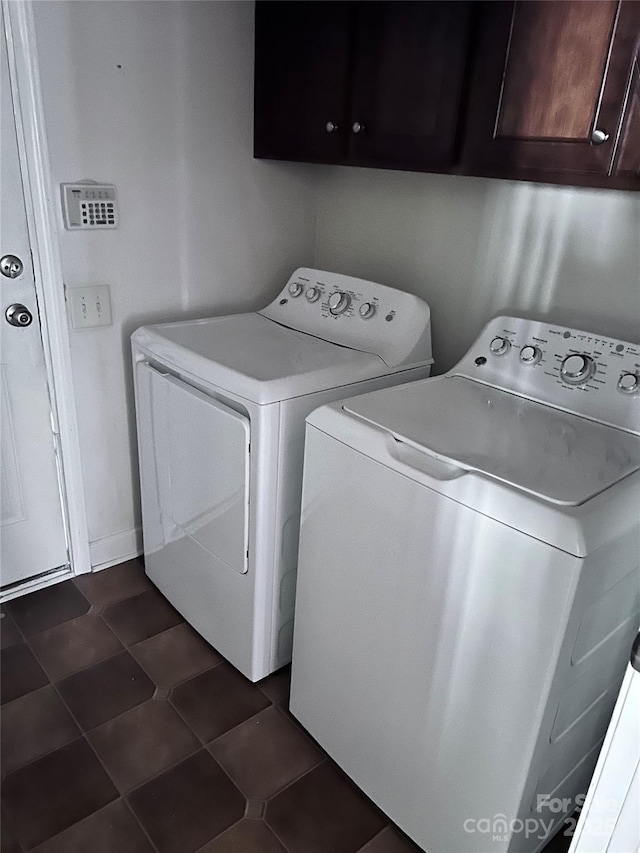 laundry room with dark tile patterned flooring, cabinet space, and separate washer and dryer