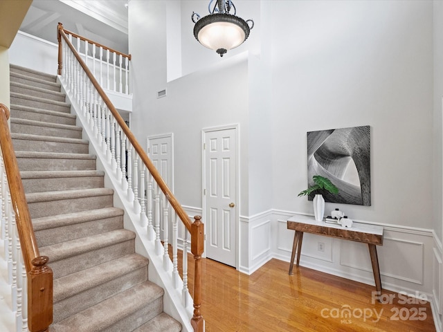 stairs with visible vents, wainscoting, a decorative wall, and wood finished floors