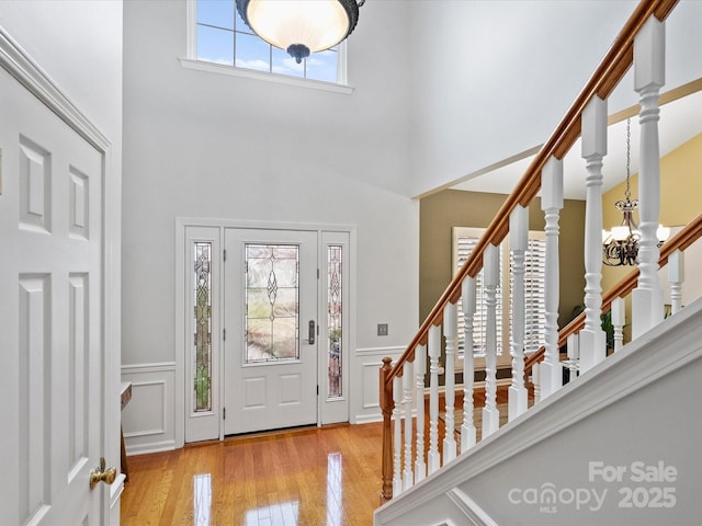 foyer featuring a notable chandelier, wainscoting, stairs, and hardwood / wood-style flooring