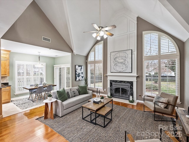 living area with plenty of natural light, visible vents, light wood finished floors, and a premium fireplace