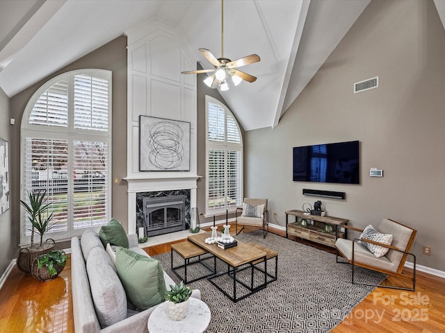 living room featuring a wealth of natural light, wood finished floors, visible vents, and a high end fireplace