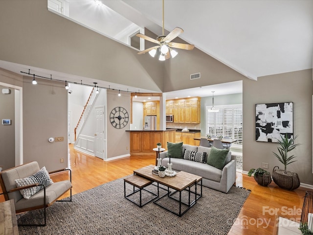 living room with visible vents, ceiling fan, light wood-type flooring, and a barn door