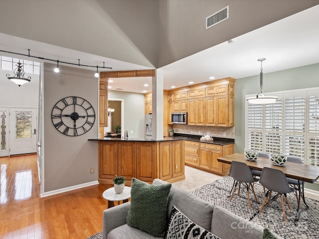 kitchen with stainless steel microwave, tasteful backsplash, dark countertops, and visible vents