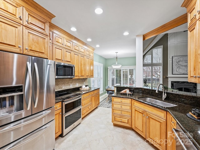 kitchen with a sink, backsplash, recessed lighting, stainless steel appliances, and dark stone counters