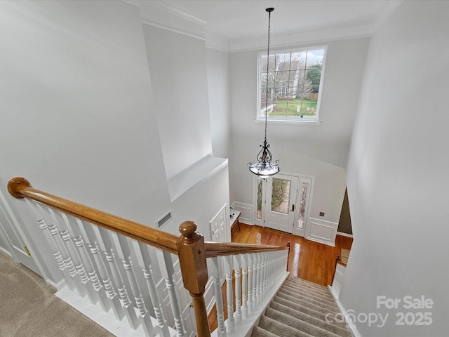 staircase with visible vents, baseboards, and ornamental molding