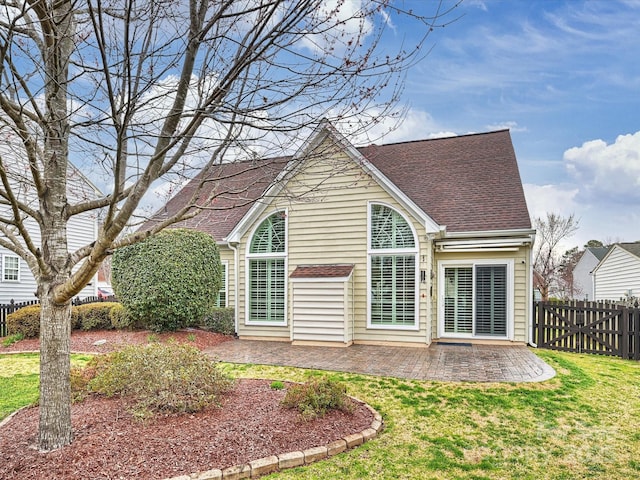 rear view of property featuring a yard, a patio area, fence, and roof with shingles