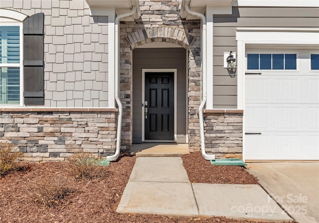 doorway to property featuring a garage and stone siding