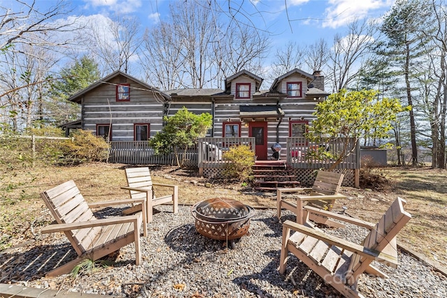 rear view of house featuring a fire pit, a deck, and a chimney