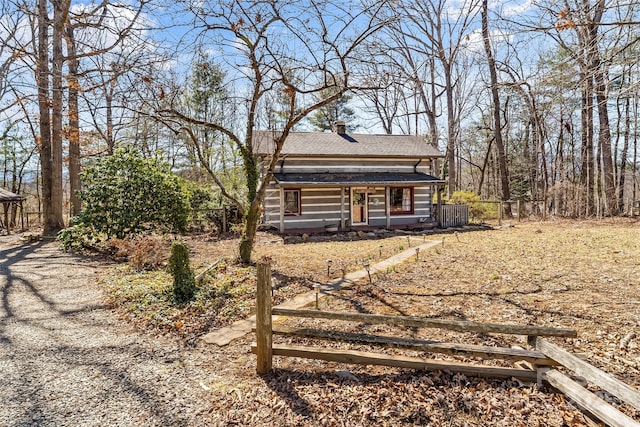 view of front of house with roof with shingles, fence, and a chimney