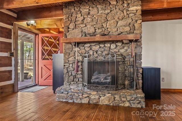 interior details featuring a stone fireplace, wood finished floors, and baseboards