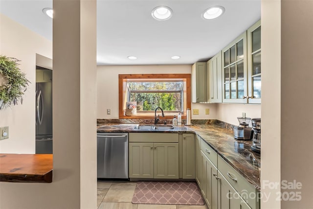 kitchen featuring glass insert cabinets, dark stone countertops, stainless steel appliances, a sink, and recessed lighting