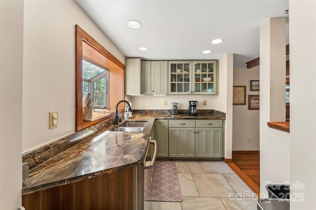 kitchen with light tile patterned floors, glass insert cabinets, a sink, and recessed lighting