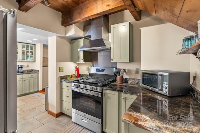 kitchen featuring beam ceiling, wall chimney exhaust hood, green cabinets, appliances with stainless steel finishes, and baseboards