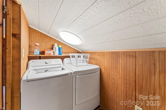 laundry room featuring wooden walls, laundry area, and washer and clothes dryer