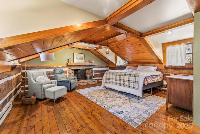 bedroom featuring lofted ceiling with beams, a stone fireplace, a baseboard radiator, and hardwood / wood-style flooring