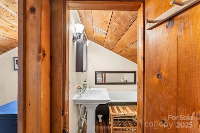 bathroom with vaulted ceiling, visible vents, and wood ceiling