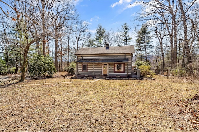 rear view of house with a chimney and fence