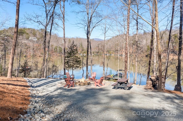 view of water feature featuring an outdoor fire pit, a floating dock, and a view of trees