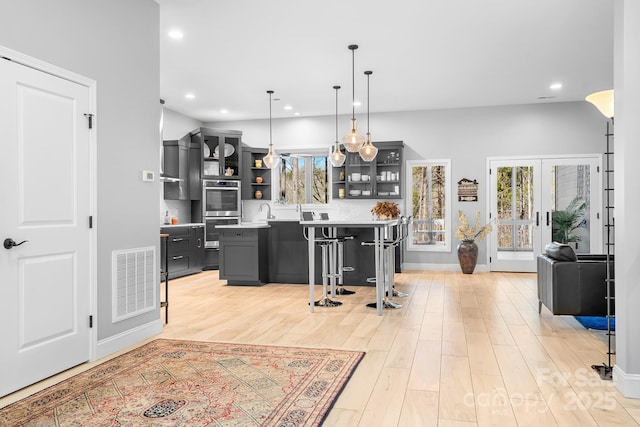 kitchen featuring open shelves, visible vents, light wood-style flooring, decorative backsplash, and double oven