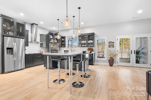 kitchen featuring stainless steel refrigerator with ice dispenser, open shelves, light countertops, decorative backsplash, and wall chimney range hood