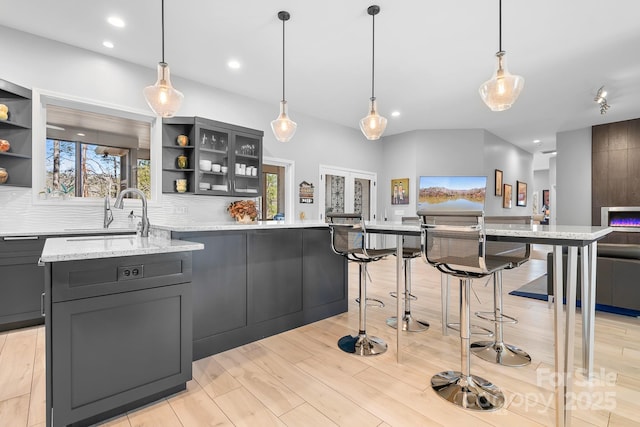 kitchen featuring tasteful backsplash, a wealth of natural light, a sink, and open shelves