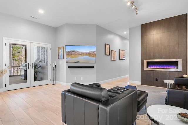 living room with french doors, a fireplace, visible vents, light wood-style floors, and baseboards