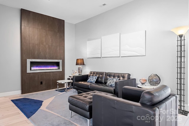 living room with light wood-type flooring, visible vents, a fireplace, and baseboards