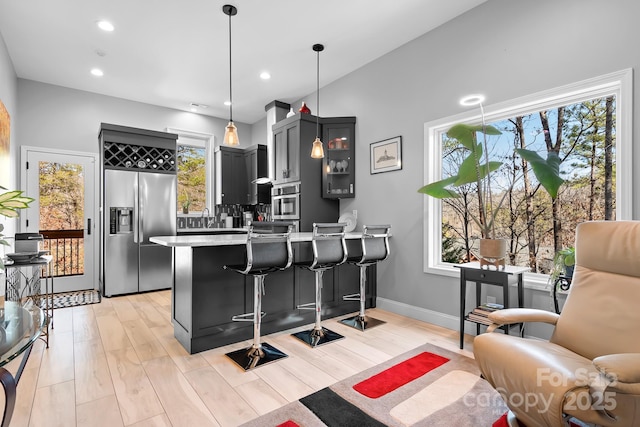 kitchen with light wood finished floors, appliances with stainless steel finishes, a breakfast bar area, a peninsula, and light countertops