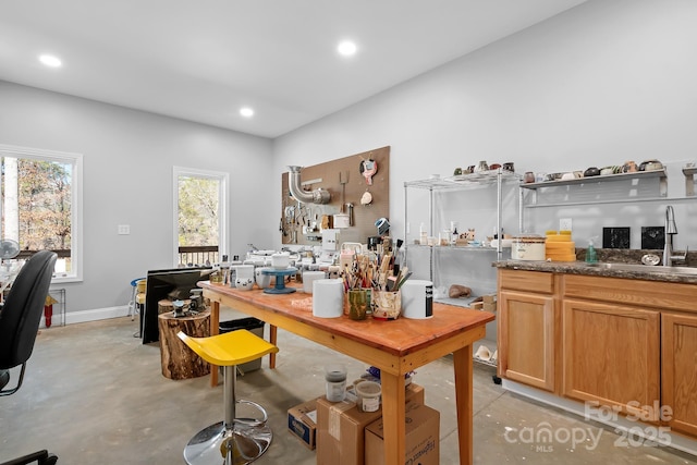 office area with concrete flooring, recessed lighting, a sink, and baseboards