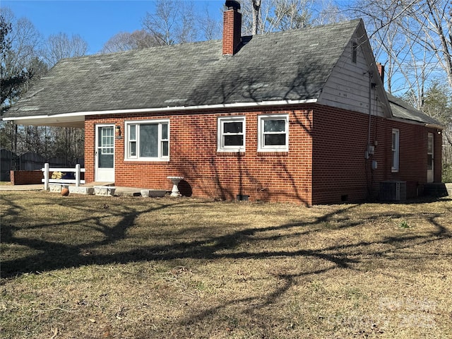 back of property with brick siding, a yard, a chimney, crawl space, and cooling unit