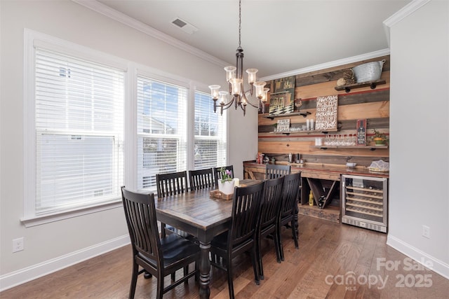 dining area with beverage cooler, ornamental molding, wood finished floors, and visible vents