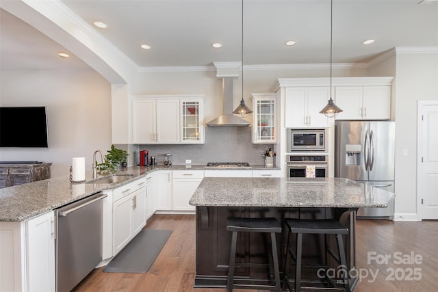 kitchen with wall chimney exhaust hood, appliances with stainless steel finishes, dark wood-style flooring, and a sink